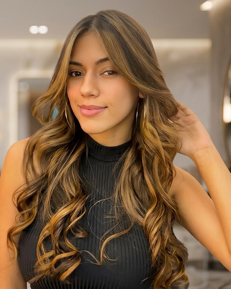 Cliente sorrindo no salão, com o cabelo longo finalizado em ondas